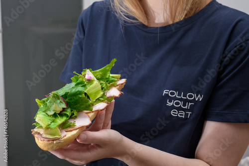 Kobieta na diecie je kanapkę z wędliną i duża ilością zielonej sałaty 