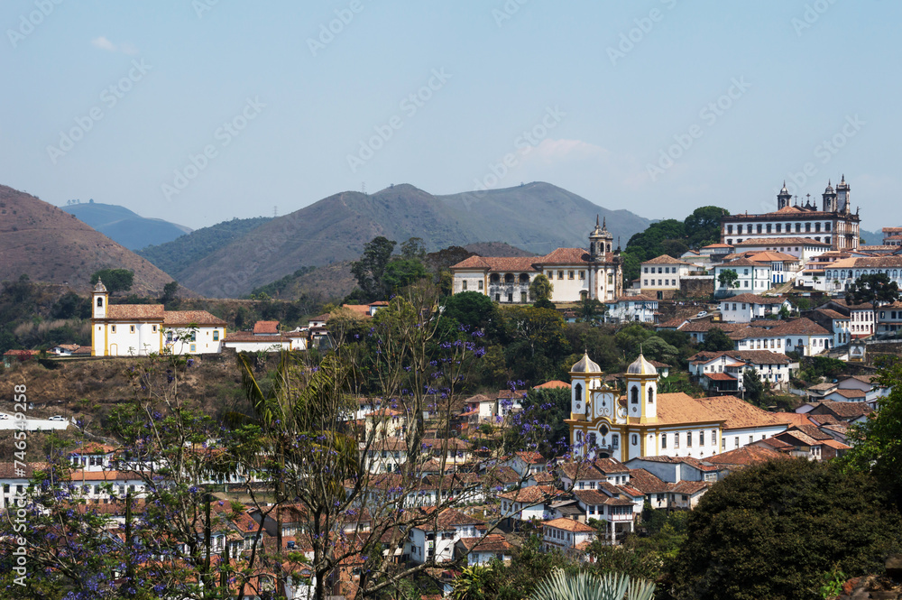 Part of the historic center of the city of Ouro Preto photographed from above showing several churches and imposing structures and mountains in the background