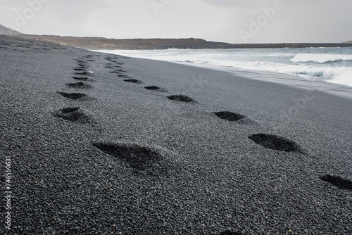 impronte sulla sabbia nera del vulcano dell'oceano  photo