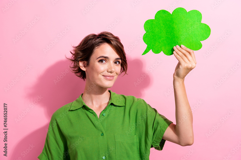 Photo portrait of attractive young woman hold paper cloud comics dressed stylish green clothes isolated on pink color background Photo portrait of attractive young woman hold paper cloud comics dressed stylish green clothes isolated on pink color background