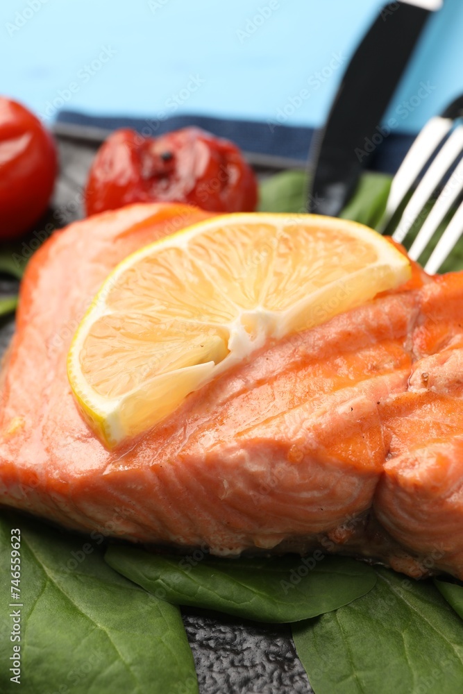 Tasty grilled salmon with tomatoes, spinach and lemon on table, closeup Tasty grilled salmon with tomatoes, spinach and lemon on table, closeup