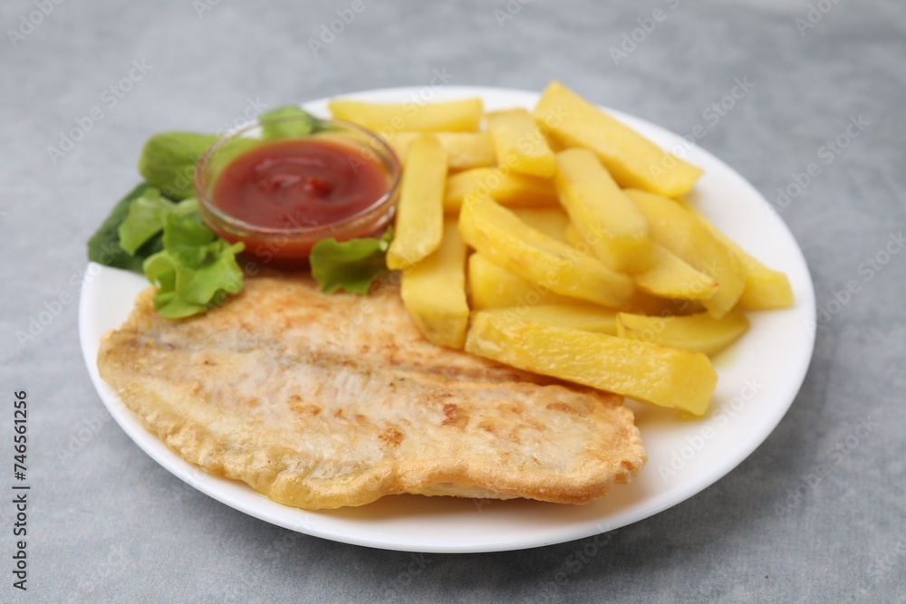 Delicious fish and chips with ketchup and lettuce on gray table, closeup Delicious fish and chips with ketchup and lettuce on gray table, closeup