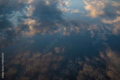 Sunset sky reflected in water. Pink clouds and blue sky reflection in still lake