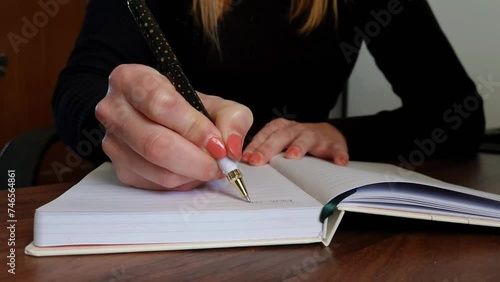 Woman’s hand with beautiful polished fingernails writing down thoughts and ideas on notebook with a pen. Slow motion video of creative woman taking notes. Concept of lifestyle, planning or journaling