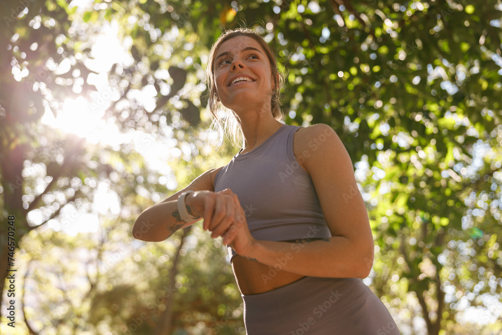 Young woman in sportswear looking on smartwatch before exercising. Outdoor sports in the morning Young woman in sportswear looking on smartwatch before exercising. Outdoor sports in the morning