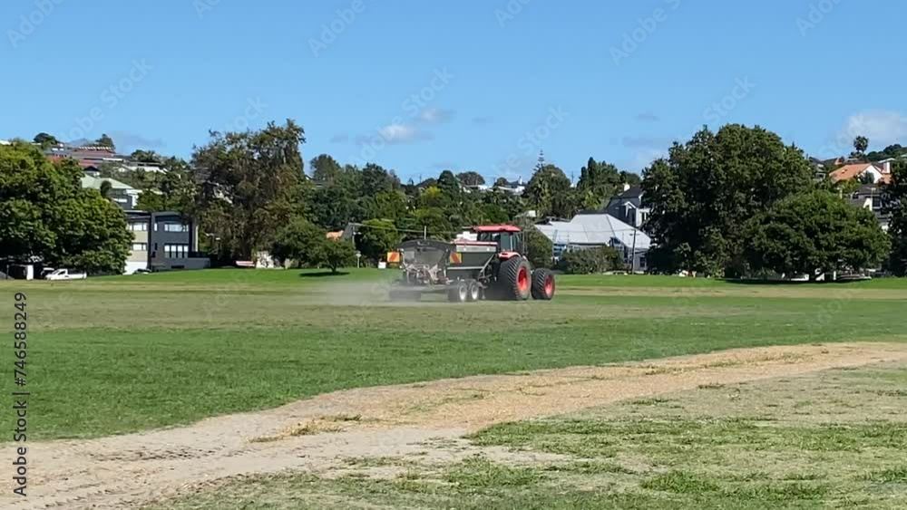 Professional special equipment, a tractor takes care of the grass on the city lawn, side view. Seasonal work concept, lawn, football field, soil aeration, lawn fertilization Professional special equipment, a tractor takes care of the grass on the city lawn, side view. Seasonal work concept, lawn, football field, soil aeration, lawn fertilization