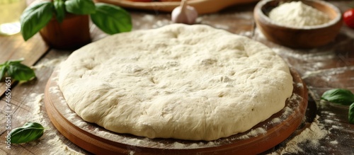 A smooth and elastic pizza dough is resting on top of a wooden cutting board, showcasing the preparation process for homemade pizza. The dough is made by combining ingredients like salt, sugar, milk