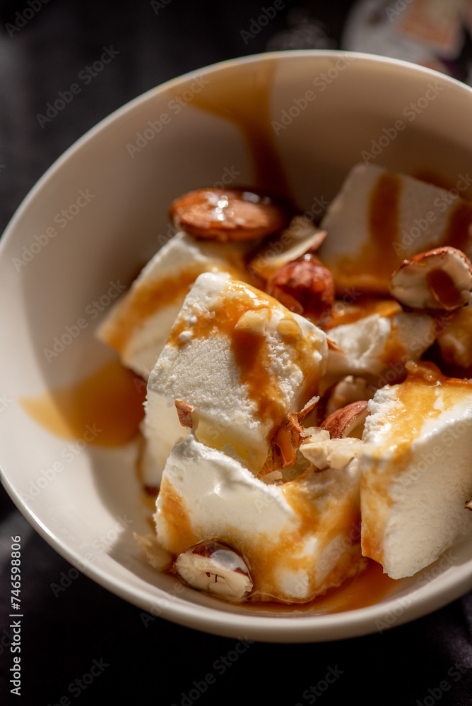 slices of ice cream with caramel syrup and almonds in a plate. homemade dessert. slices of ice cream with caramel syrup and almonds in a plate. homemade dessert.