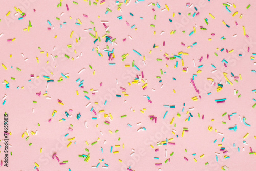 Trendy pattern of colorful sprinkles on pink background. Concept for decoration cake and bakery. 