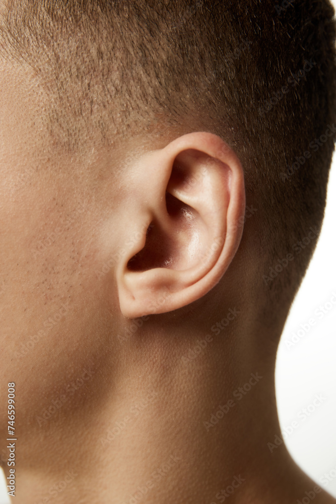 Obraz premium Close-up of male ear with detailed view of auricle and earlobe against white studio background. Concept of beauty procedures, male health, body care, spa treatment, hygiene.