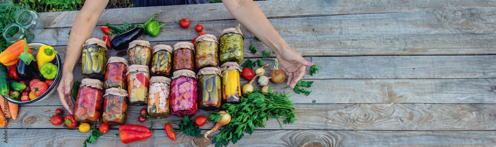 Woman canning vegetables in jars on the background of nature. preparations for the winter