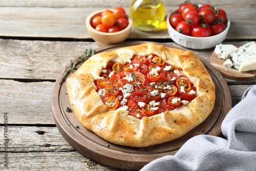 Tasty galette with tomato, thyme and cheese (Caprese galette) on wooden table, closeup. Space for text