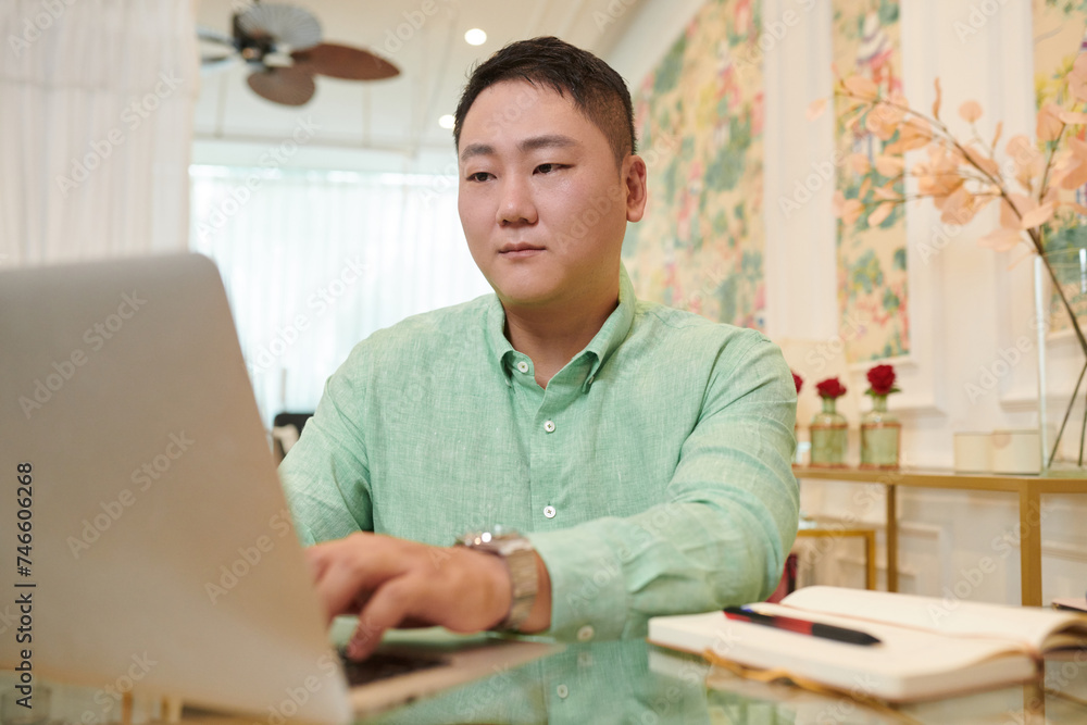 Korean spa salon owner working on laptop, checking appointments and paying bills online Korean spa salon owner working on laptop, checking appointments and paying bills online