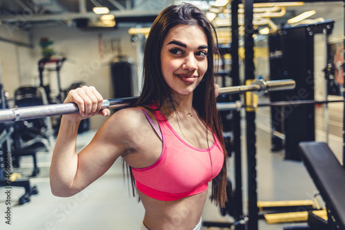Woman at gym, weight lifting and barbell for muscle building endurance, strong body and balance power in fitness. Commitment, motivation and bodybuilder in workout challenge for health and wellness.