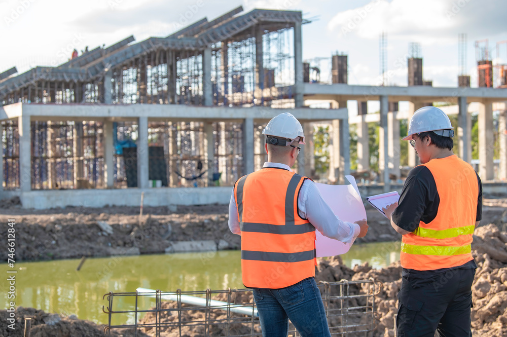 Two Asian engineer working at site of a large building project,Thailand people,Work overtime at construction site,Team of engineer discus at site