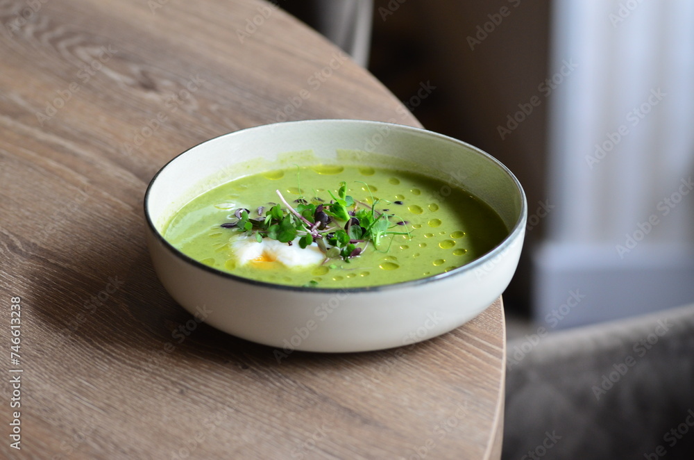 GREEN FRESH PEA ASPARAGUS CREAM SOUP SERVED ON WOODEN TABLE IN RESTAURANT, HEALTHY FOOD BACKGROUND, CLOSE VIEW GREEN FRESH PEA ASPARAGUS CREAM SOUP SERVED ON WOODEN TABLE IN RESTAURANT, HEALTHY FOOD BACKGROUND, CLOSE VIEW