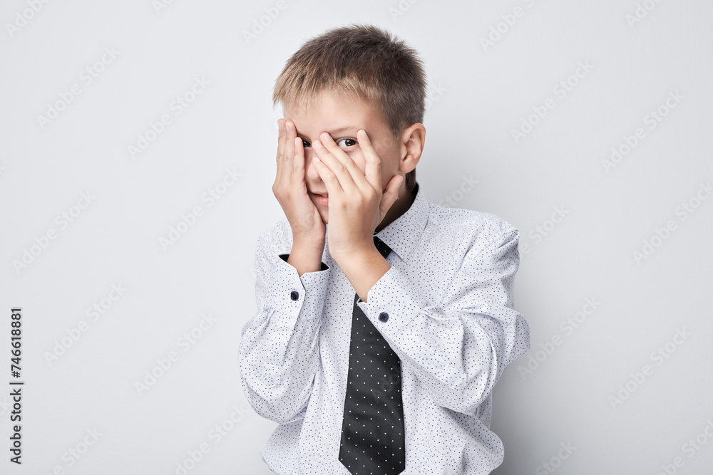 Scared young boy covering face with hands, isolated on a gray background. Scared young boy covering face with hands, isolated on a gray background.