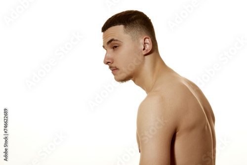 Side view photo of young man slouches against white studio background. Incorrect posture, beauty and confidence. Concept of beauty treatment, male health, body care, spa treatment, hygiene. photo