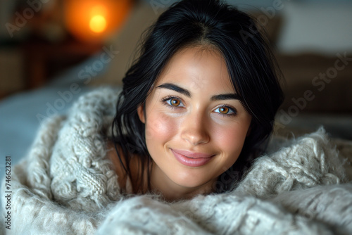 Smiling woman with black hair lying on bed at home