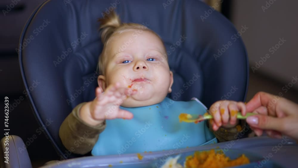 Adorable Caucasian baby takes the spoon from mom's hand. Little kid puts the spoon to his mouth. Close up. Adorable Caucasian baby takes the spoon from mom's hand. Little kid puts the spoon to his mouth. Close up.
