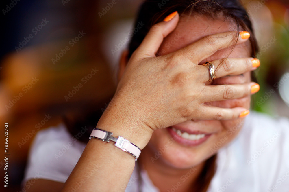 Fototapeta premium Playful shy woman hiding face with her hand. .