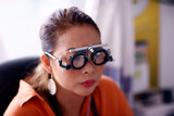 Portrait of young woman during eye examination test glasses goggles at optometrist optician clinic.