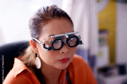 Portrait of young woman during eye examination test glasses goggles at optometrist optician clinic.