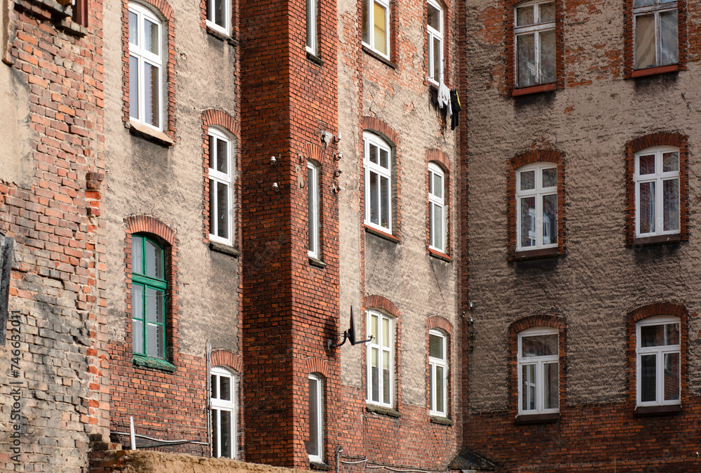 Obraz premium Windows in a red brick building, old building with falling plaster.