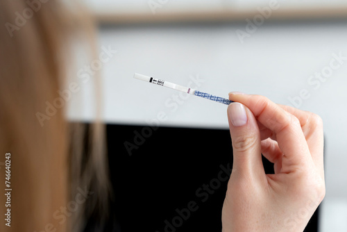 A woman holds a pregnancy test with a negative result