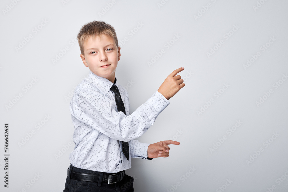 Portrait boy in school uniform pointing with finger at empty space for product advertising or text Portrait boy in school uniform pointing with finger at empty space for product advertising or text