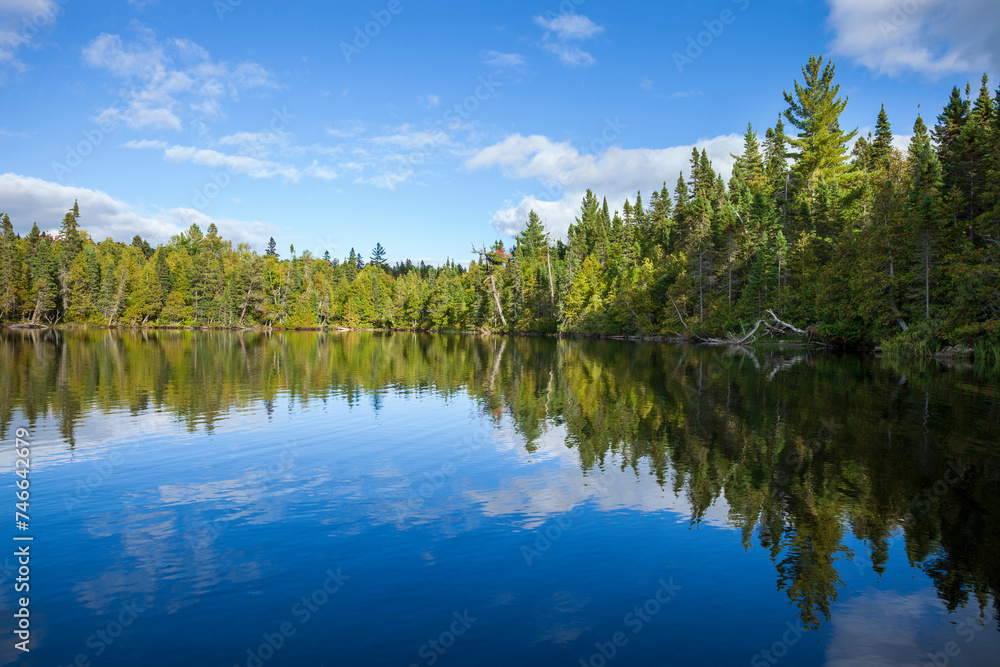 Blue lake in northern Minnesota with pines along the sunlit shore during autumn