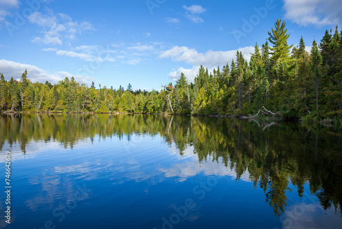 Blue lake in northern Minnesota with pines along the sunlit shore during autumn