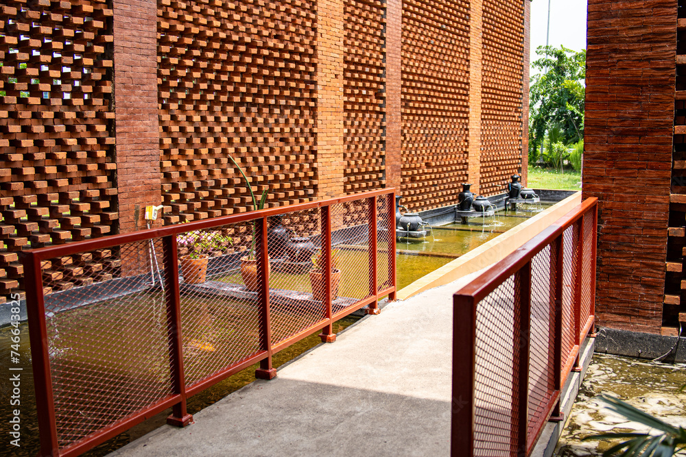 Fototapeta premium Exposed red brick facade with pond and small fountains.