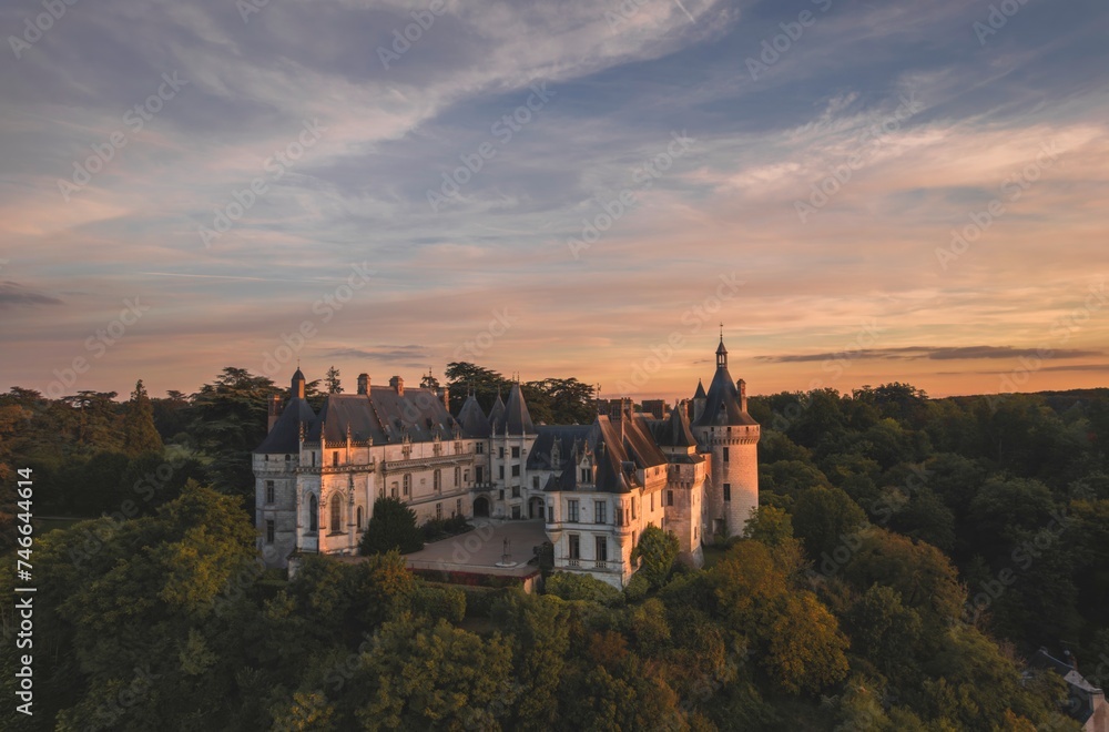 A breathtaking aerial view showcases the grandeur of Le Chateau de Chaumont-sur-Loire nestled among lush green trees, creating a scene straight out of a fairy tale