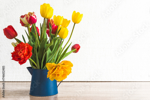Bunch of multicolored tulips in blule vase on a white background; copy space; Spring greeting card template