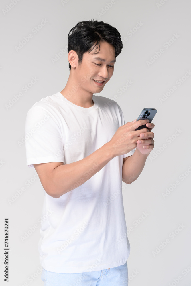 Portrait of young smiling asian man using smartphone over white background Portrait of young smiling asian man using smartphone over white background