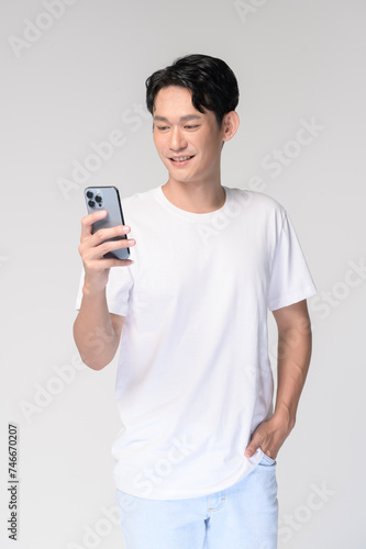 Portrait of young smiling asian man using smartphone over white background © tonefotografia