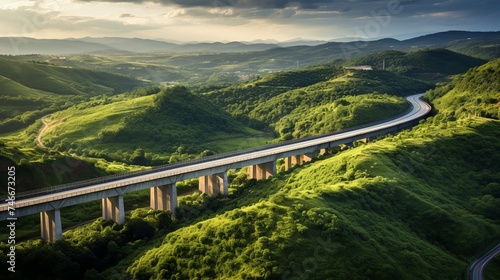 Aerial view of highway road bridge for vehicular transport as part of infrastructure development built over valley with green forest trees and hills connecting towns during sunset photo