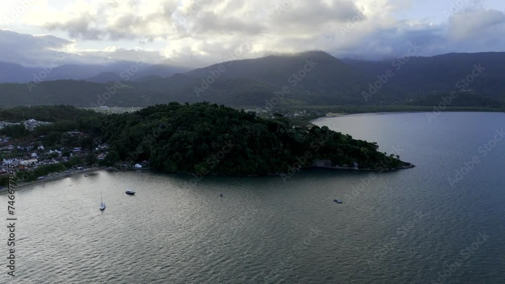 Aerial shot drone flies toward forested peninsula at sunset Aerial shot drone flies toward forested peninsula at sunset
