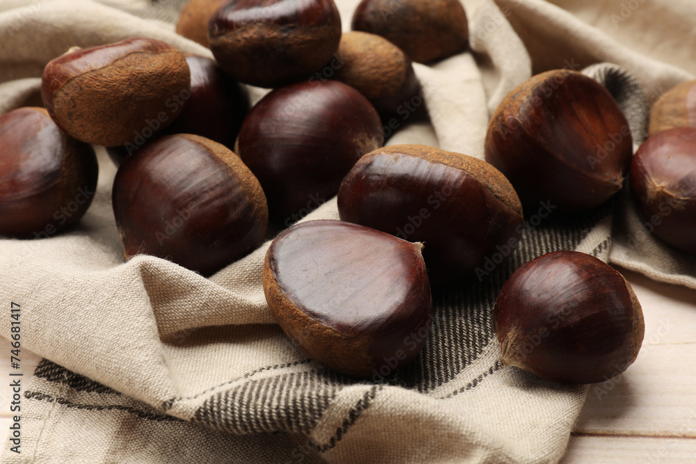 Fototapeta premium Sweet fresh edible chestnuts on light wooden table, closeup