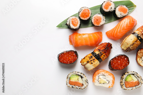 Different tasty sushi rolls on white background, flat lay. Space for text