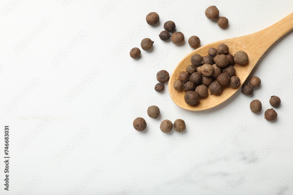 Dry allspice berries (Jamaica pepper) and spoon on white marble table, top view. Space for text Dry allspice berries (Jamaica pepper) and spoon on white marble table, top view. Space for text