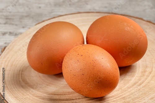 Close-up of brown, brown eggs on wooden board and background.