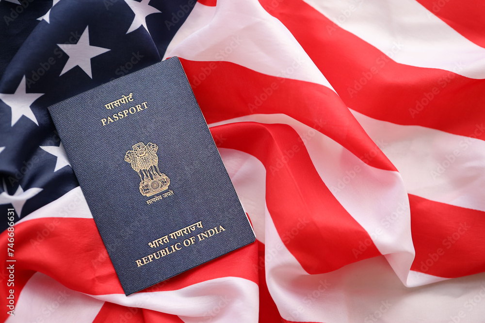 Fototapeta premium Blue Indian passport on United States national flag background close up. Tourism and diplomacy concept