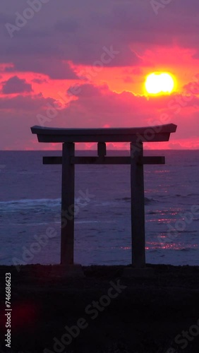 Sun Rising Over a Torii Gate Standing in the Sea photo