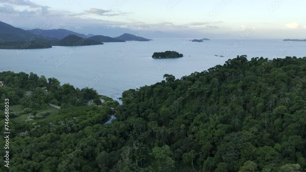 Aerial shot drone flies over forest toward open sea with islands and hills covered in trees Aerial shot drone flies over forest toward open sea with islands and hills covered in trees