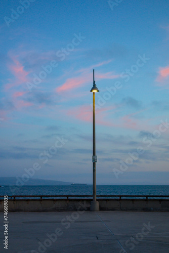 Light post shining on the Vencie Pier during dusk.