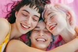 Top view of young female friends hugging each other with smiles and laughter over pink background