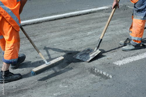 Workers asphalting repairing road on street using asphalt trowels
