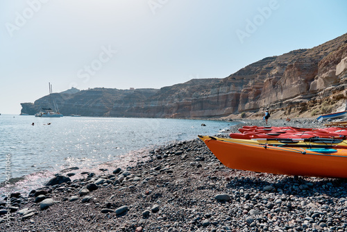 Colored kayaks lie in a row on the black sand beach (Mesa Pigadia beach). Greek Islands, Santorini, European Vacation